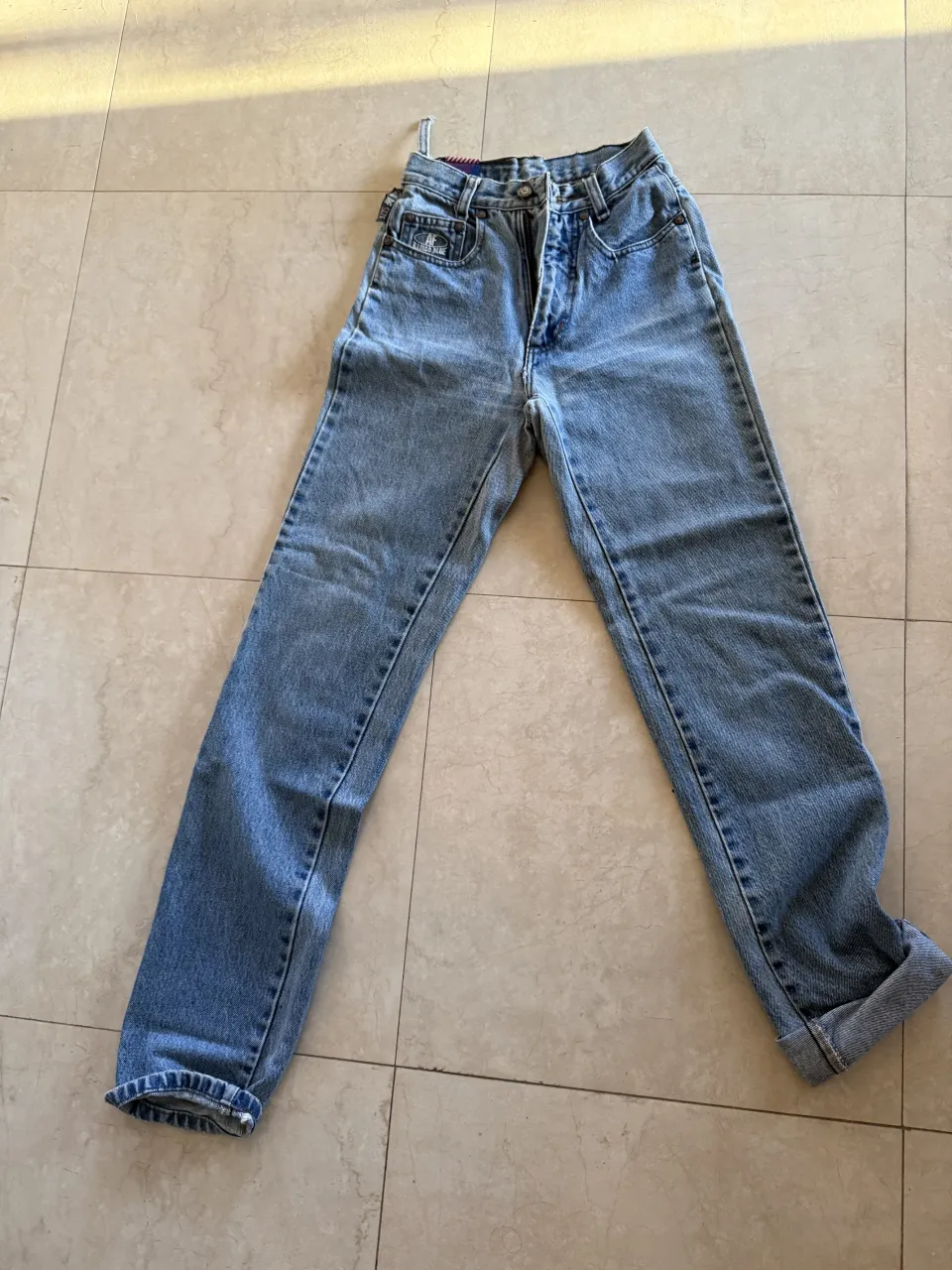 Jeans de tiro alto, color azul claro, con roturas y dobladillo en los tobillos.