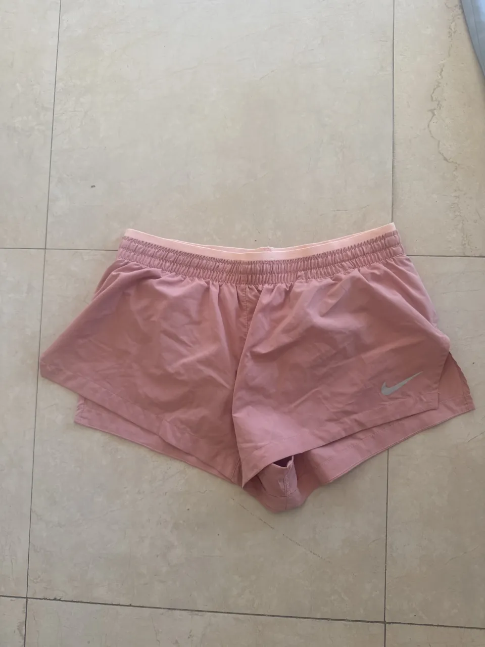 Shorts deportivos color rosa. Cintura elastizada con cordón interno. Logo de la marca plateado en un lateral.