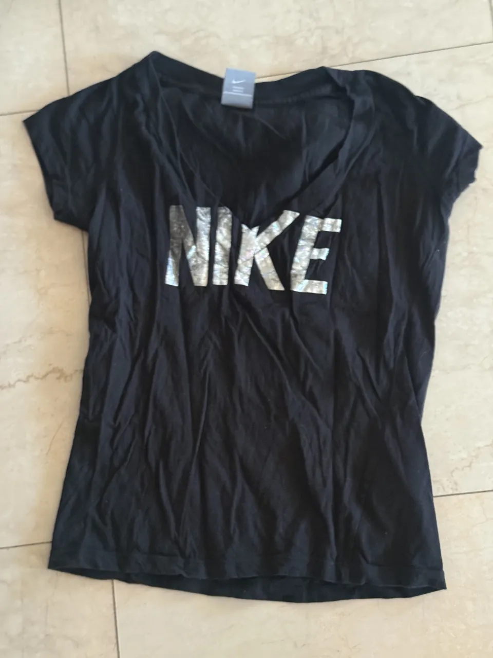 Remera negra de manga corta con logo de Nike plateado en el frente.