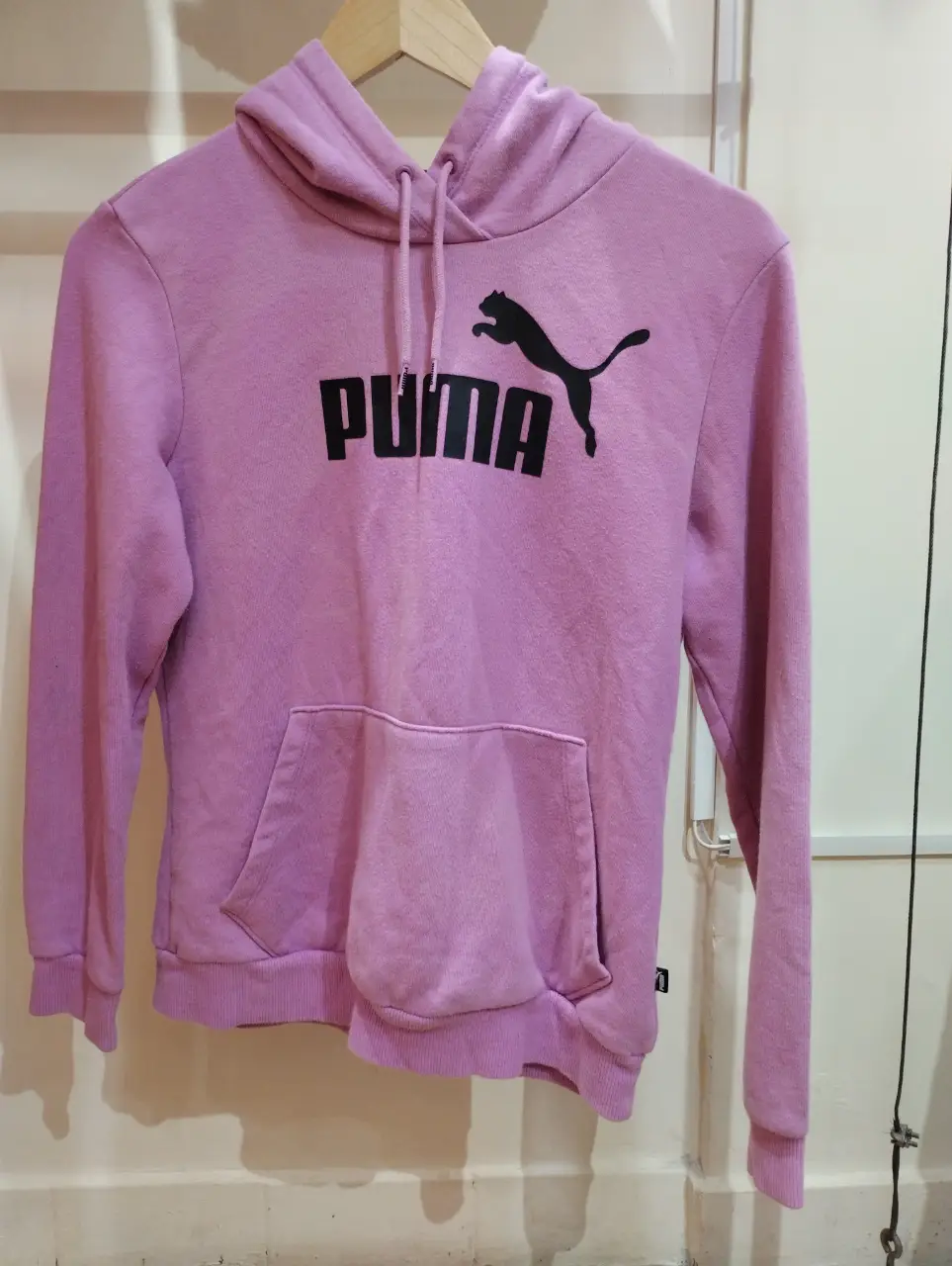 Buzo canguro Puma de color rosa, con el logo de la marca en negro en el frente. Talle S.