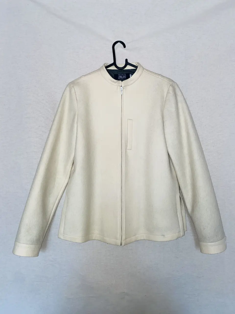 Campera de paño color crudo con cierre frontal y cuello redondo. Posee un bolsillo vertical en el frente y mangas largas con puños. Ideal para un look elegante y abrigado. es talle M 