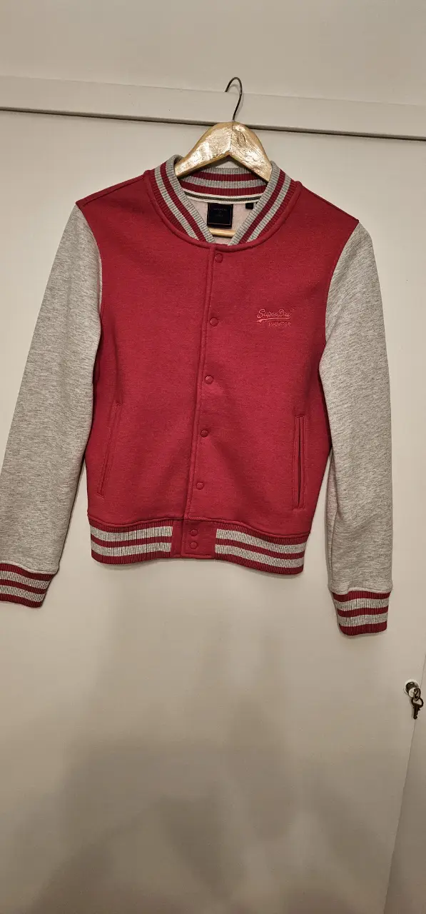 Buzo tipo colegial Superdry rojo con mangas grises. Ideal para un look casual y abrigado.