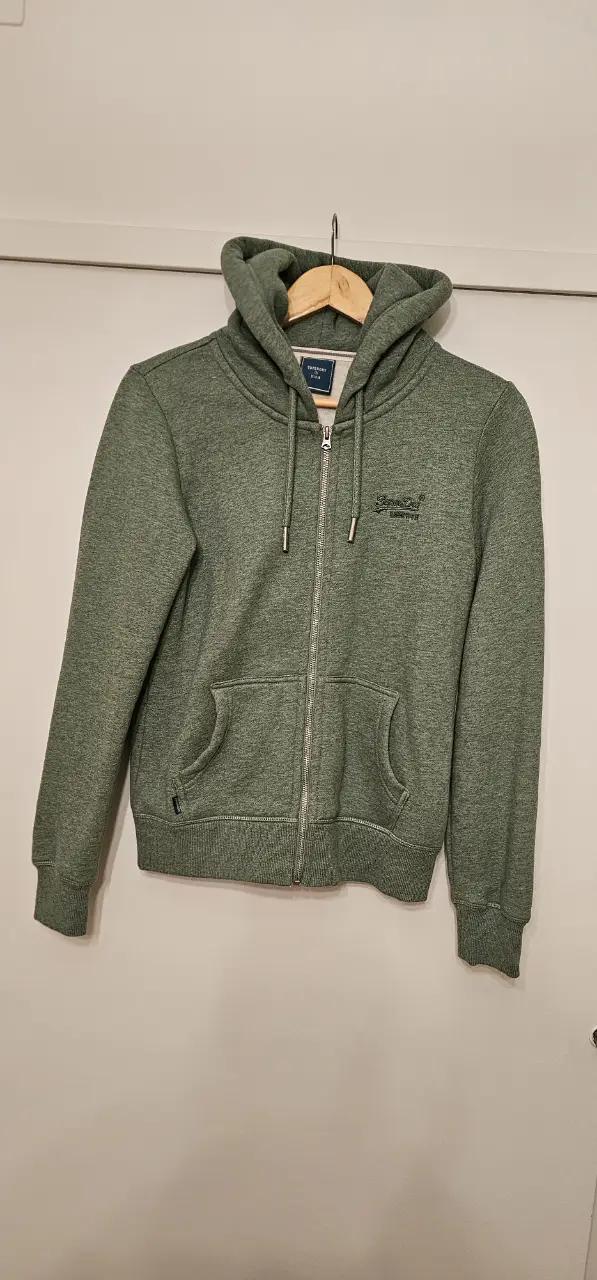 Buzo con cierre verde, ideal para un look casual y cómodo. Confeccionado en un tejido suave y de alta calidad, este buzo ofrece un ajuste perfecto y un estilo versátil para cualquier ocasión.
