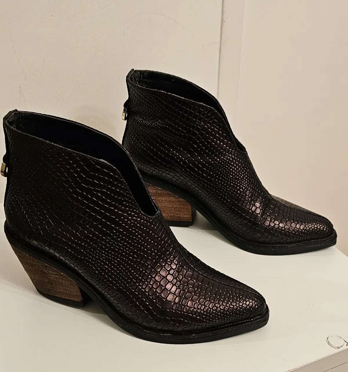 Botines de cuero sintético con diseño de reptil. Tienen un corte en V en el empeine y un taco de madera. Ideales para un look moderno y sofisticado.