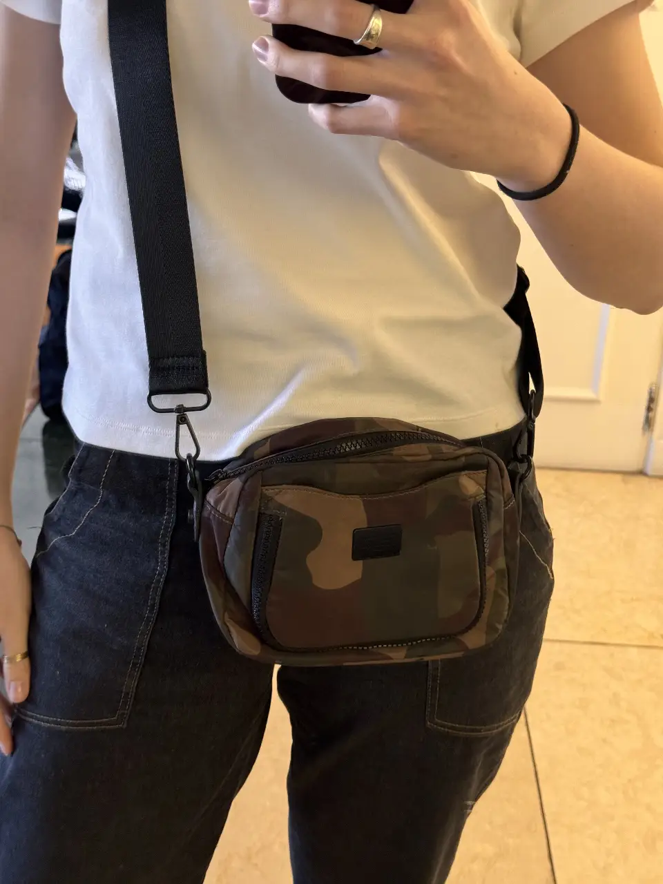 Bandolera con estampado camuflado, ideal para llevar lo esencial. Cuenta con un bolsillo frontal y correa ajustable.