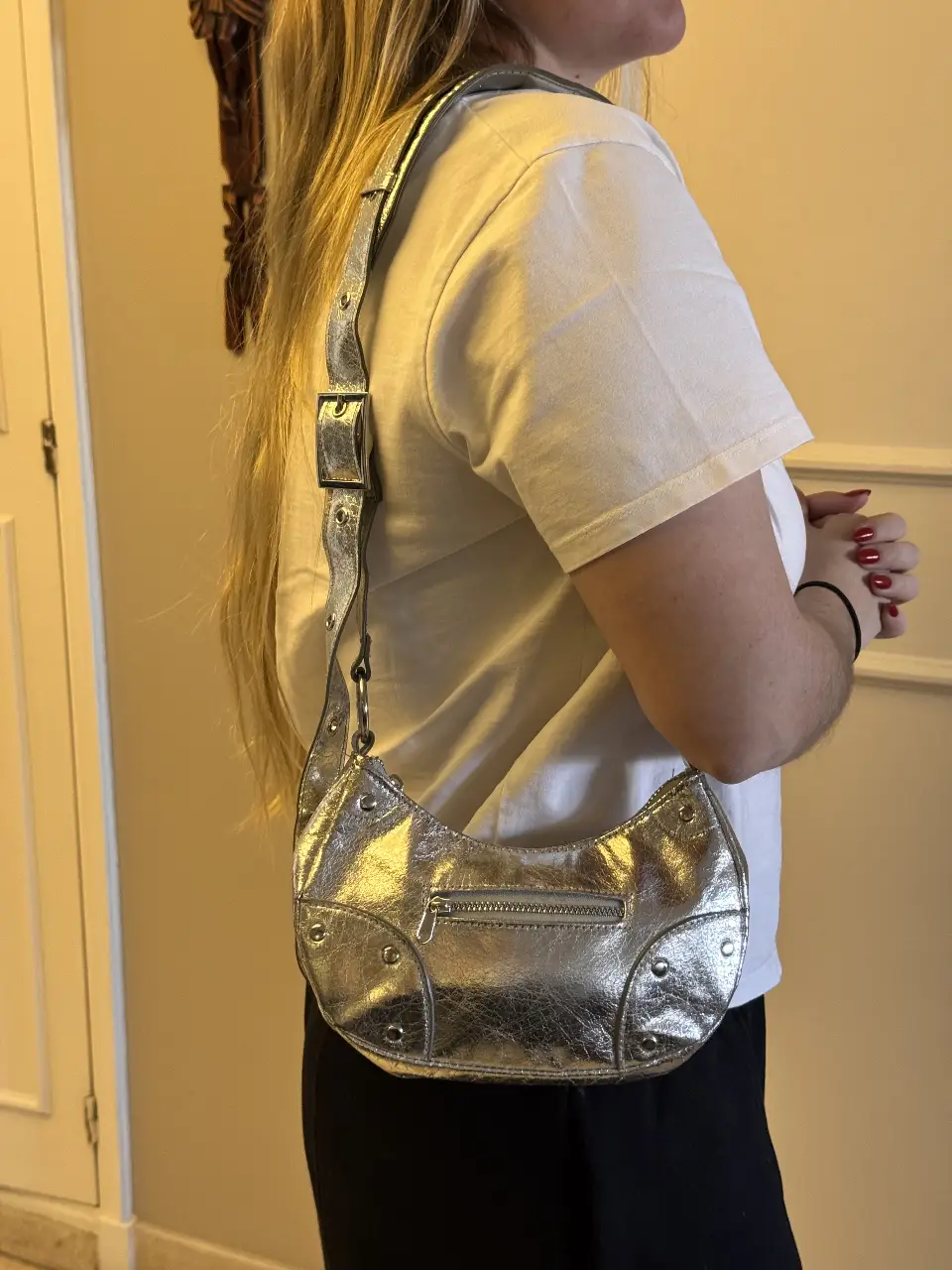 Cartera bandolera plateada con detalles de tachas. Ideal para un look moderno y canchero. Cuenta con cierre y correa ajustable.