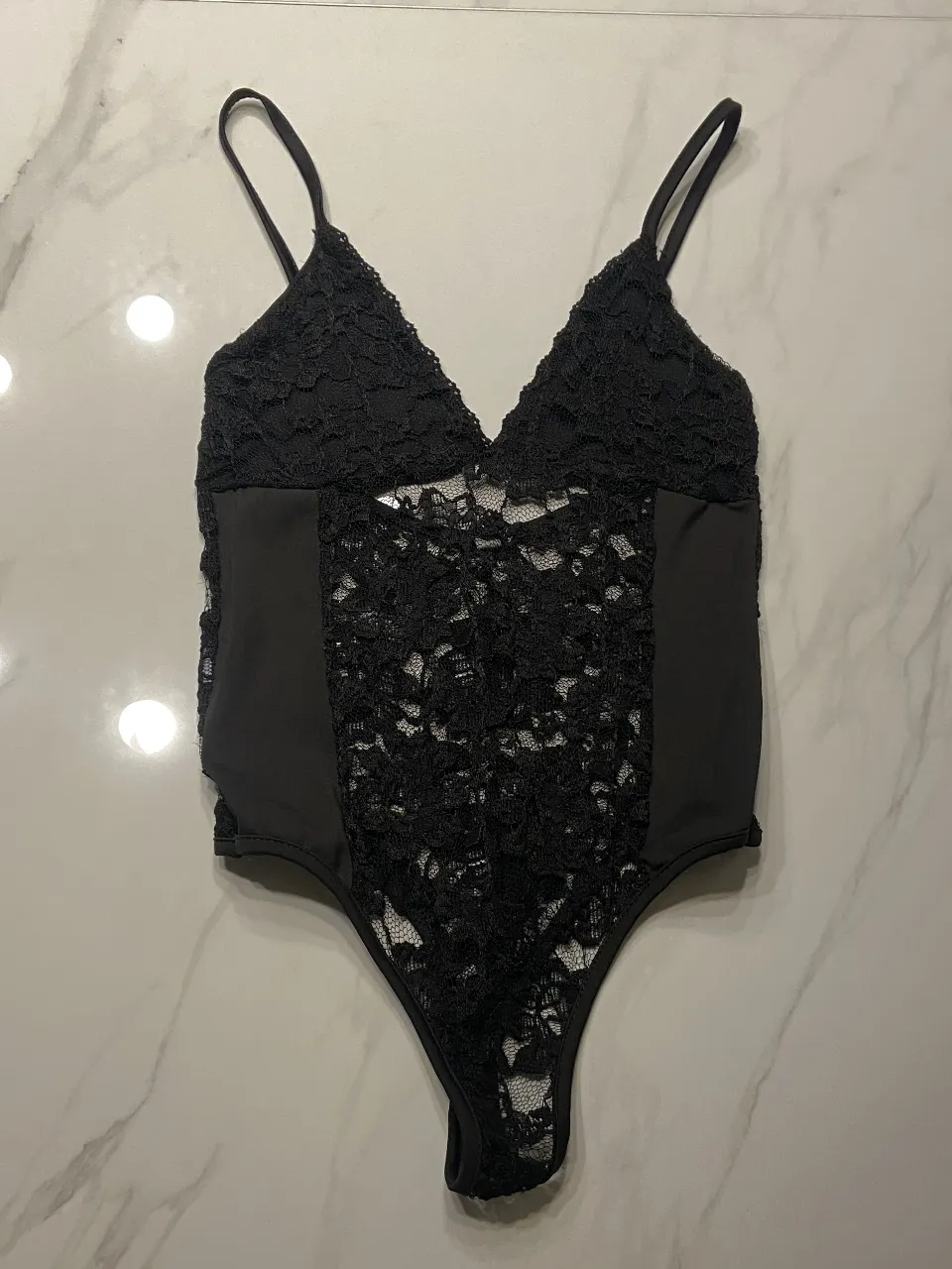 Body de encaje negro con tirantes finos y escote en V. Ideal para una ocasión especial o para darle un toque sensual a tu look.