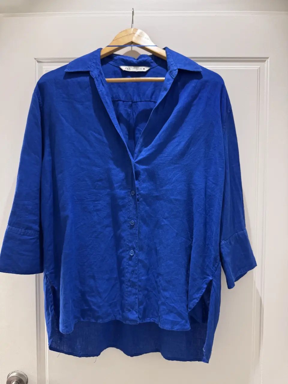 Camisa de lino azul, manga 3/4, con cuello y botones. Ideal para un look casual y fresco.