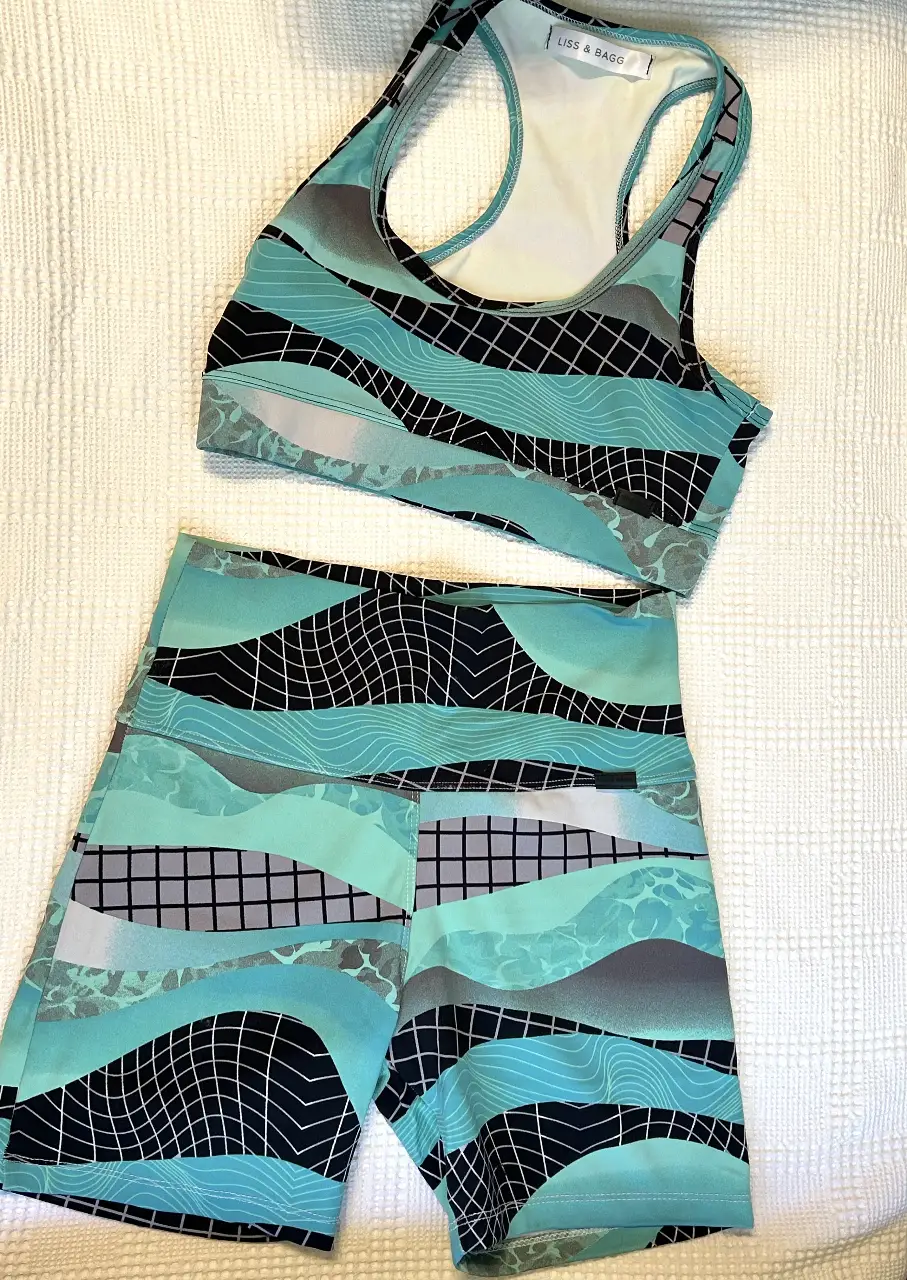 Conjunto deportivo de mujer, top y short con estampado abstracto en tonos turquesa, negro y gris. Ideal para entrenamientos y actividades físicas.