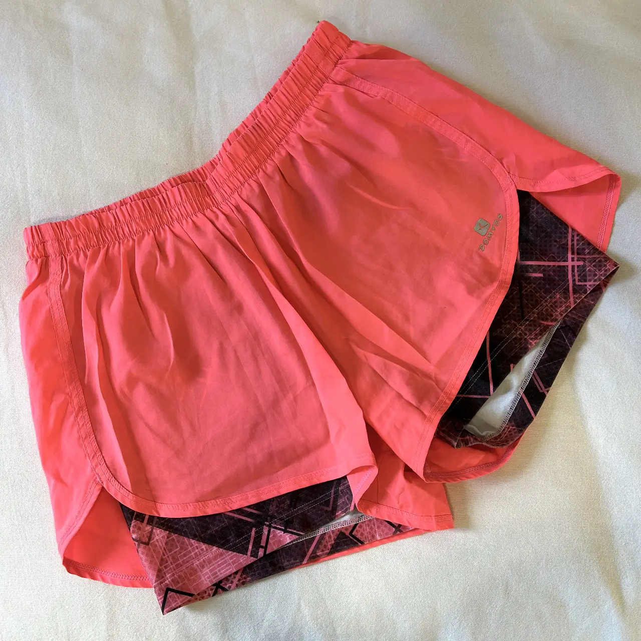 Short deportivo de mujer, color naranja con interior negro estampado. Ideal para running y actividades físicas.