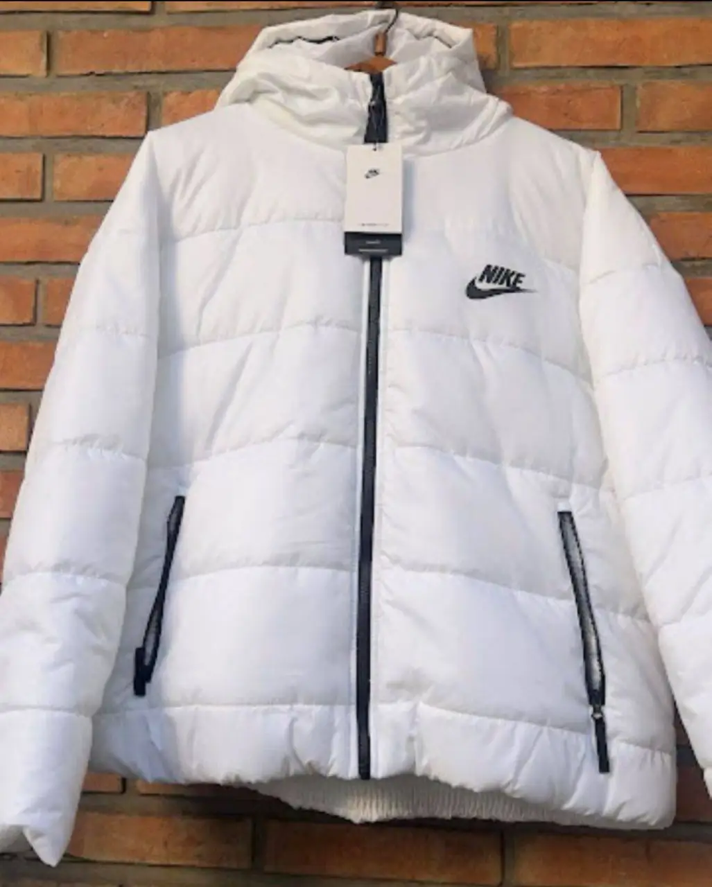 Campera Nike blanca con capucha y cierre. Ideal para el invierno, con diseño acolchado y logo de la marca. Perfecta para un look deportivo y abrigado.