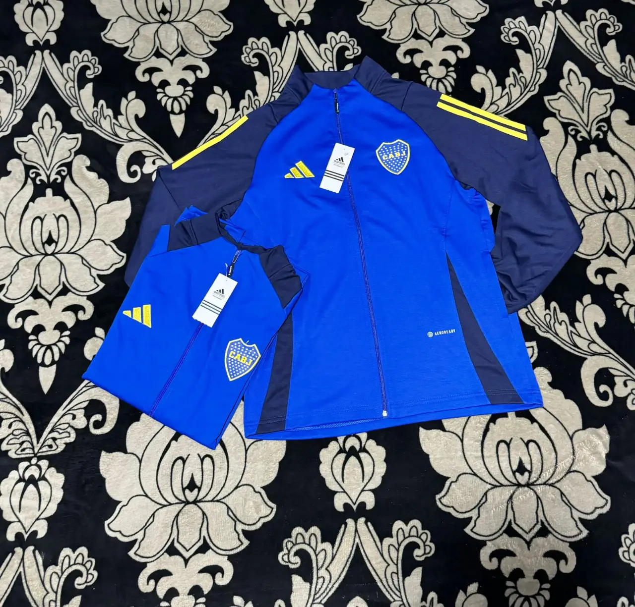 Buzo con cierre Adidas del Club Atlético Boca Juniors. Ideal para entrenar o usar en el día a día. Con el escudo del club y detalles en amarillo.