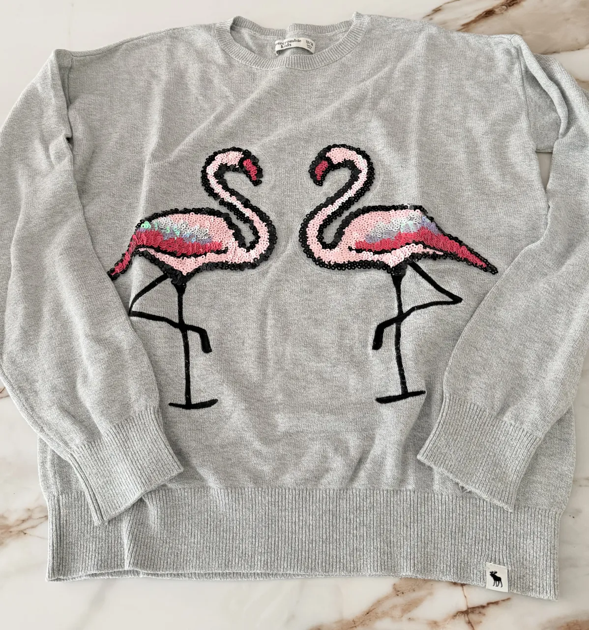 Sweater gris con dos flamencos bordados con lentejuelas. Ideal para un look canchero y divertido.