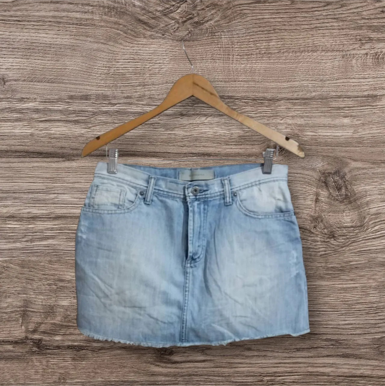 pollera de jean celeste claro de mujer, tiro medio, con detalles de desgaste y la marca Rapsodia. Ideal para un look casual y moderno.