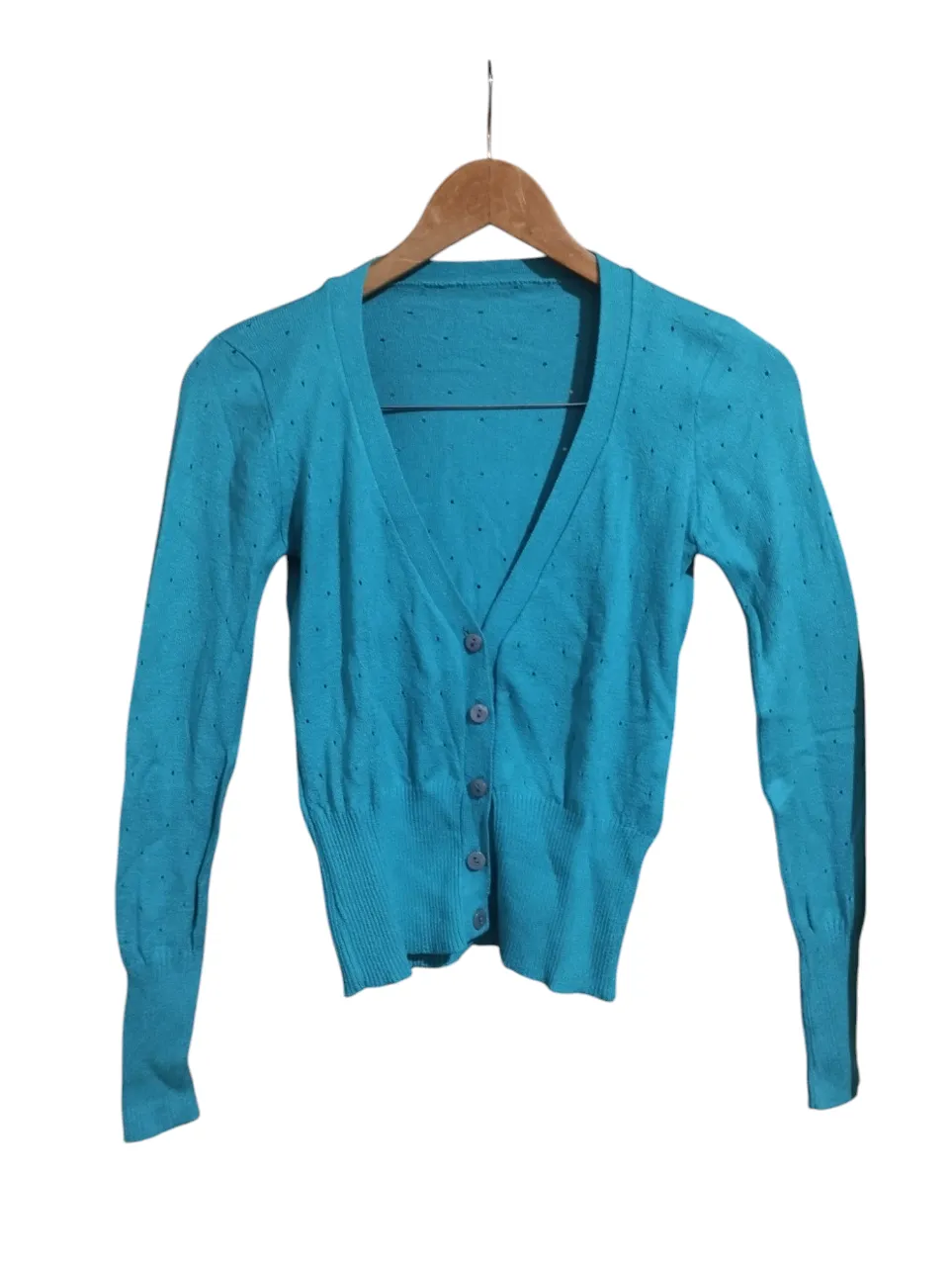 Cardigan azul con botones y pequeños detalles calados en toda la prenda. Mangas largas y cuello en V.