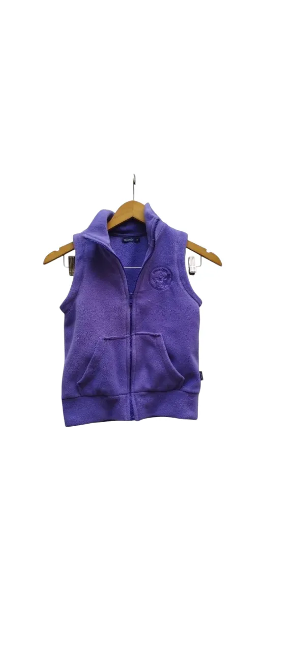Chaleco de polar violeta, ideal para abrigarse en días frescos. Tiene cuello alto y un bolsillo canguro al frente. Perfecto para un look casual y cómodo.
