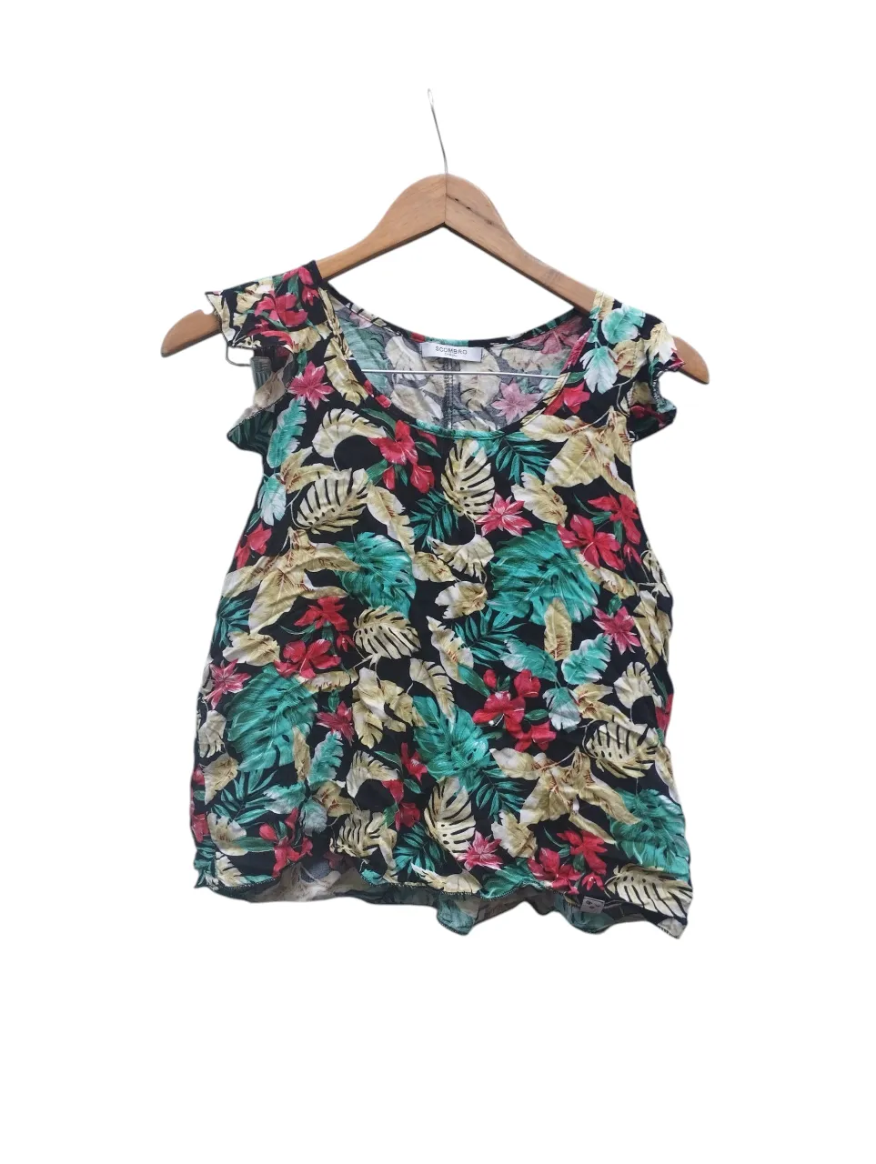 Remera estampada con flores y hojas tropicales en fondo negro. Posee mangas cortas con volados.