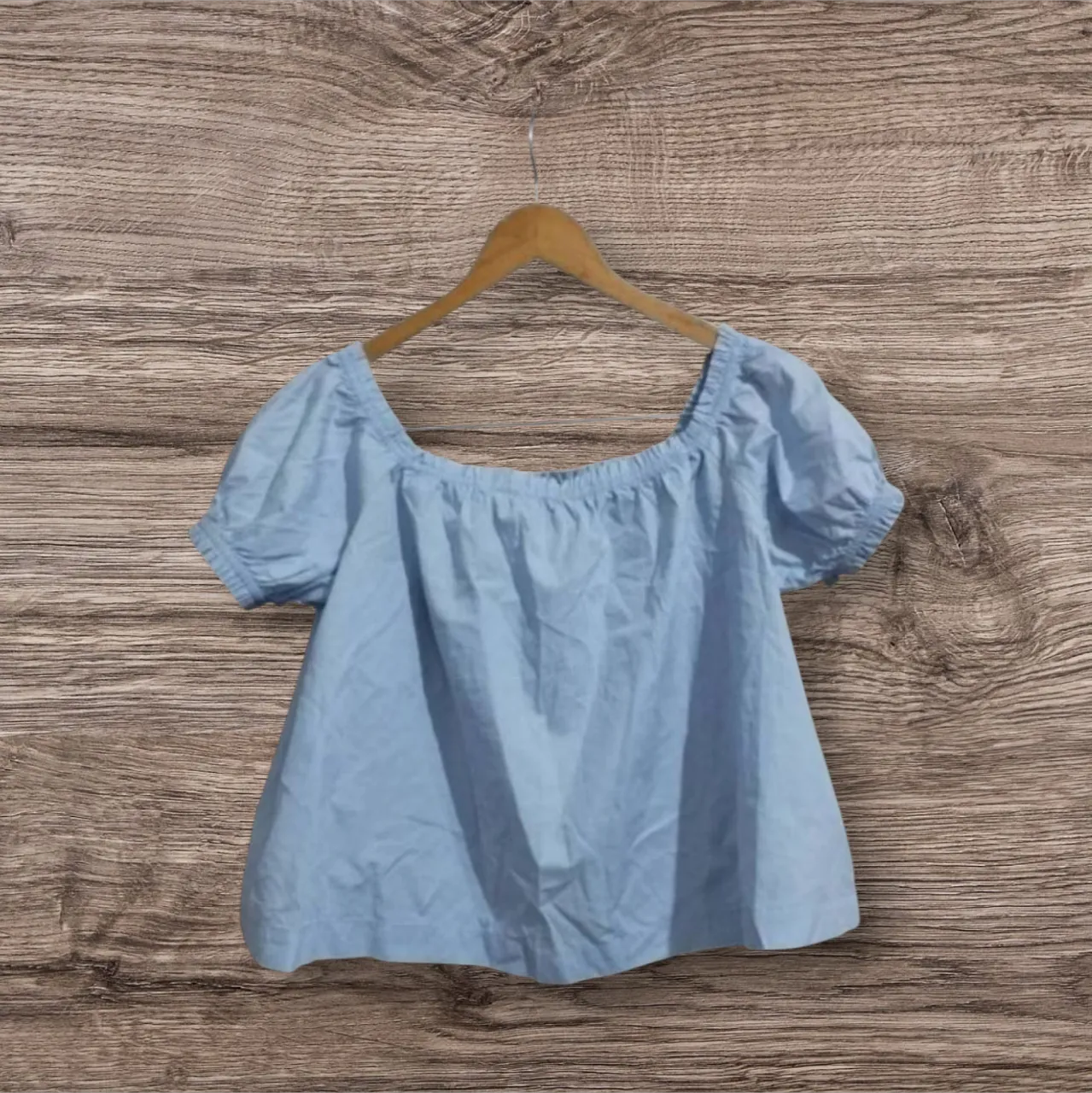Blusa celeste de mujer, con mangas cortas abullonadas y escote cuadrado. Ideal para un look fresco y femenino.