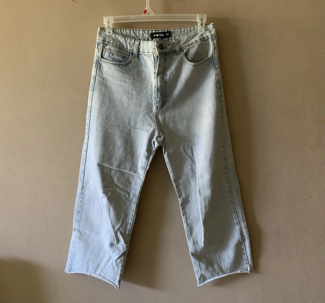 Jean estilo culotte (wide leg crop) de tiro alto, marca Pieta. Confeccionado íntegramente en denim rígido de alta calidad en tono celeste claro con terminación de ruedo al corte (desflecado). Posee calce holgado desde la cadera con pierna ancha y corta, ideal para lucir calzado. Estado impecable, sin detalles de uso ni desgaste. Si bien la etiqueta marca 44, la moldería es pequeña, recomendada para un talle 40 o 42 según el calce deseado.