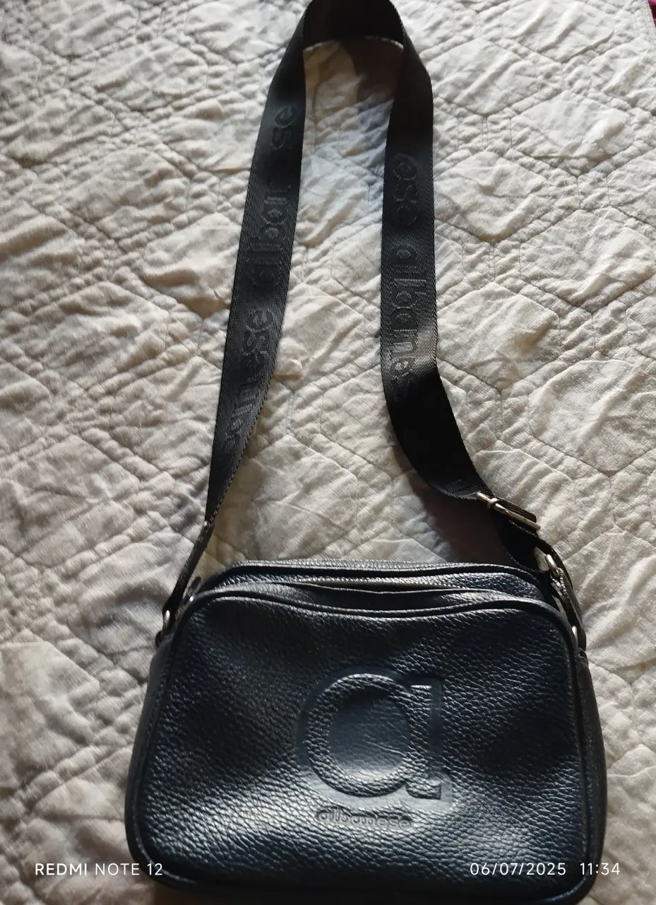 Bandolera azul con correa ajustable y logo de la marca en relieve. Ideal para llevar tus esenciales con estilo y comodidad.