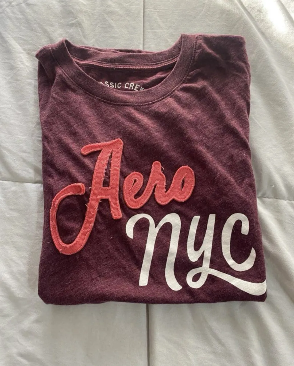 Remera de manga corta Aero NYC para mujer, de color borgoña con estampado en relieve. Ideal para un look casual y urbano.