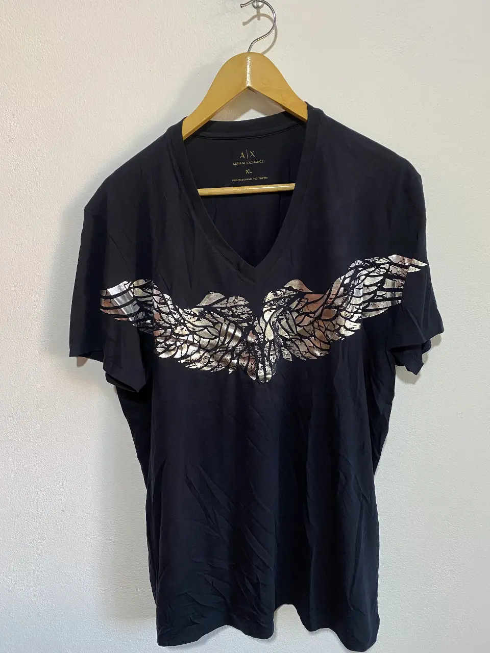 Armani Exchange. Remera azul de hombre con cuello en V y estampado plateado de alas en el frente. Marca Armani Exchange, talle XL, 100% algodón Pima. Ideal para un look casual y canchero.