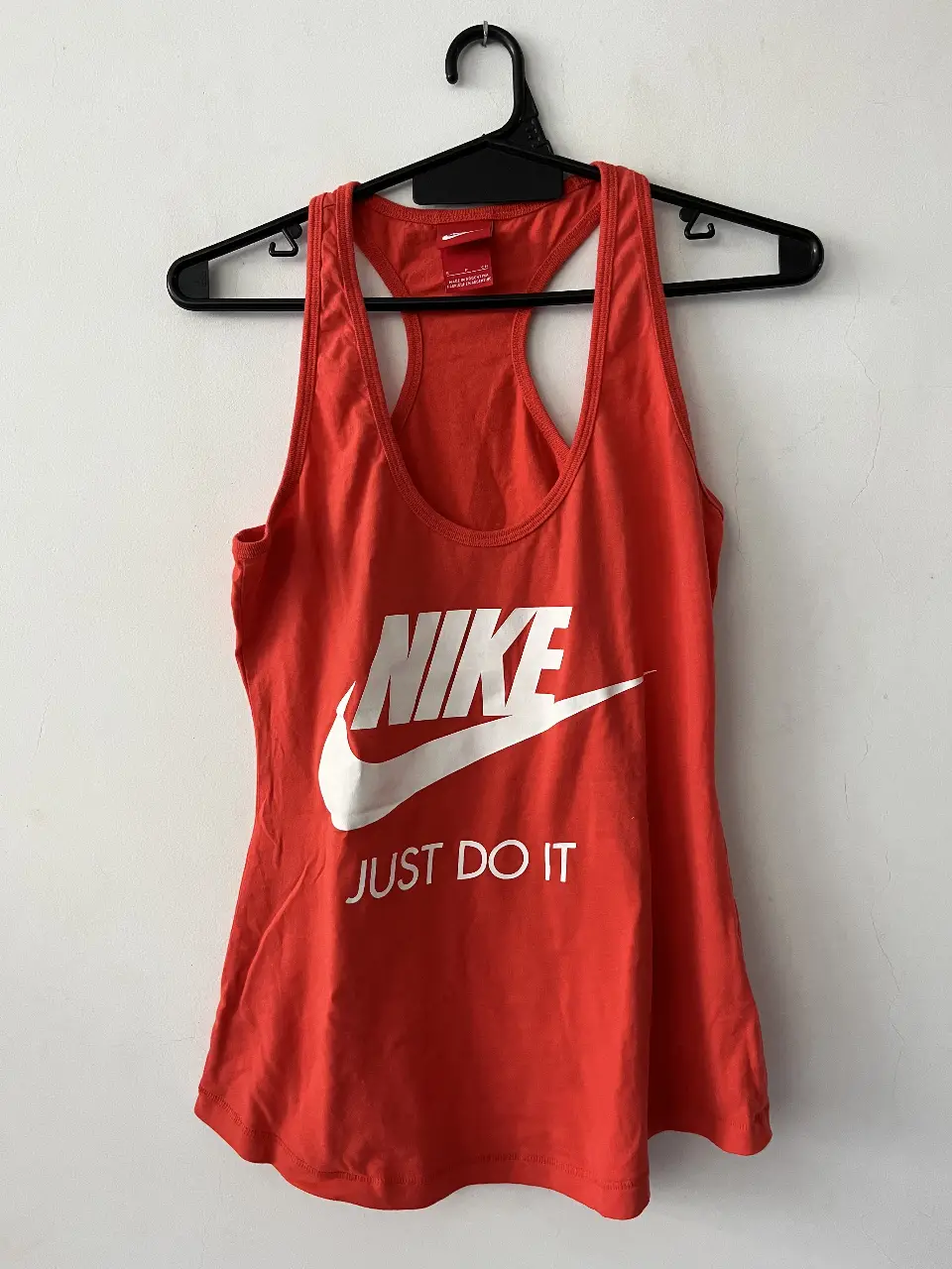 Musculosa deportiva Nike naranja con logo blanco "Just Do It". Ideal para entrenamientos y actividades físicas.