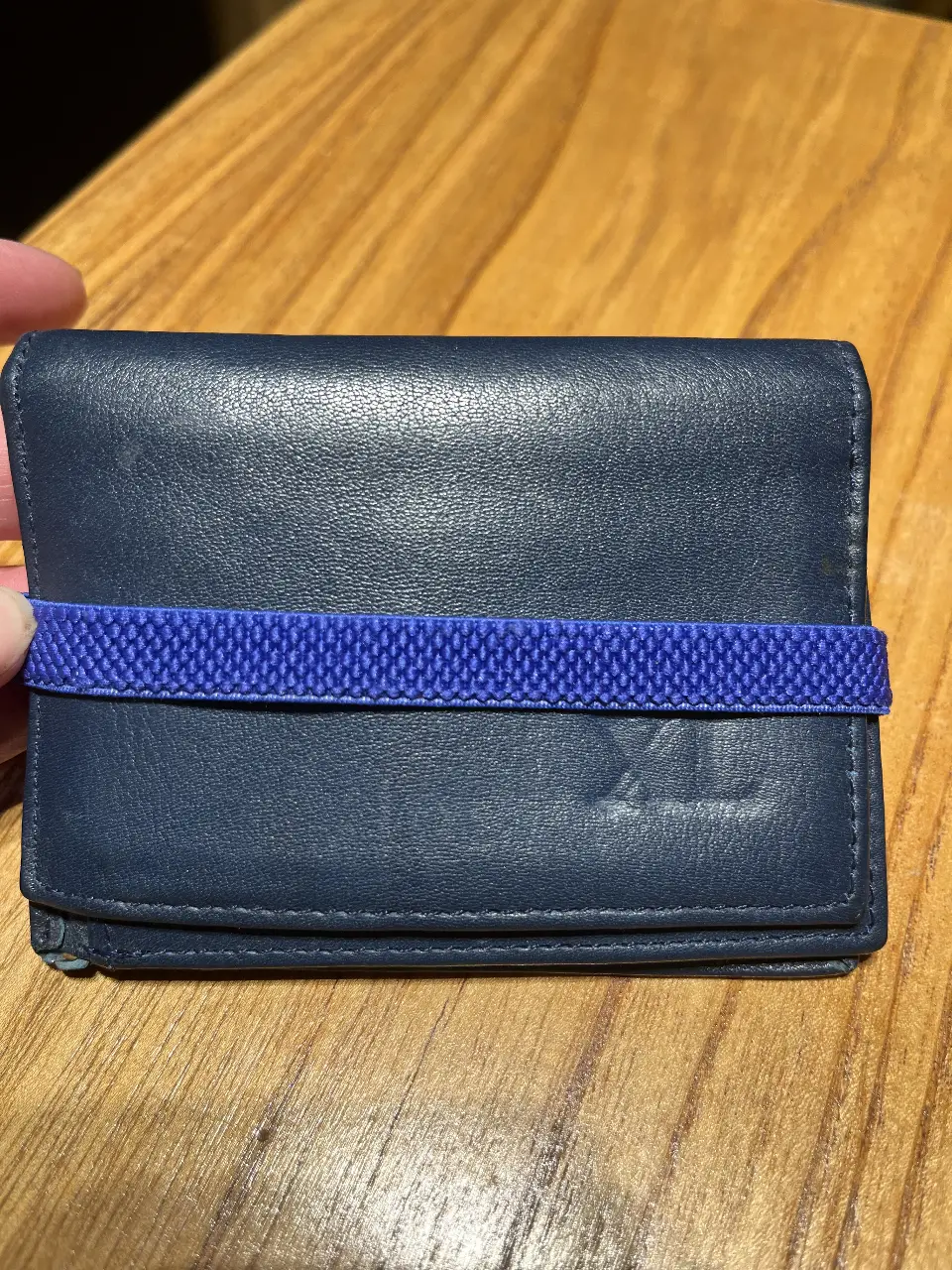 Billetera de cuero azul con banda elástica azul. Diseño compacto y funcional, ideal para llevar tarjetas y efectivo.