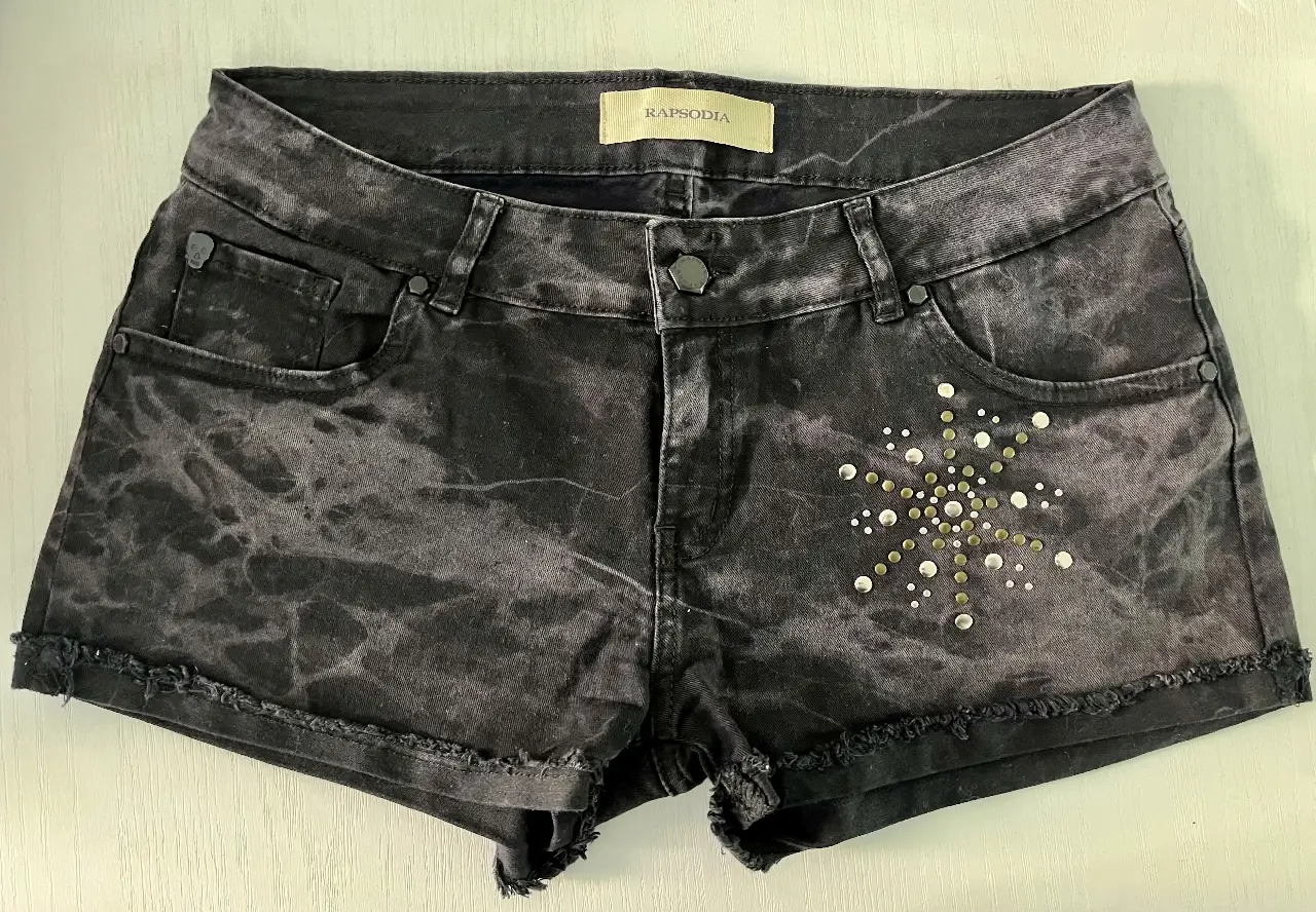 Short de jean negro con efecto gastado y detalles de tachas. Tiro medio, ideal para un look casual y canchero.