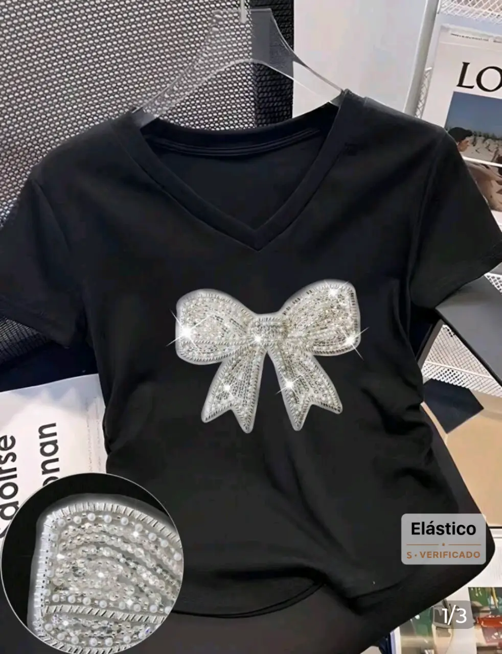 Remera negra con cuello en V y aplique de moño con brillos. Ideal para un look elegante y sofisticado.