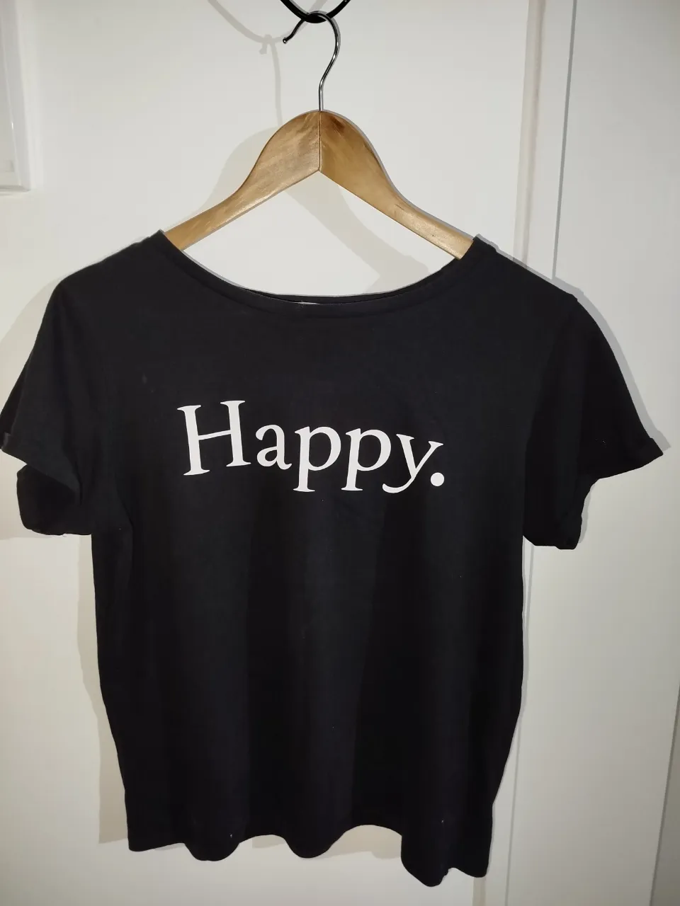 Remera negra de algodón con estampado "Happy" en blanco. Ideal para un look casual y cómodo.