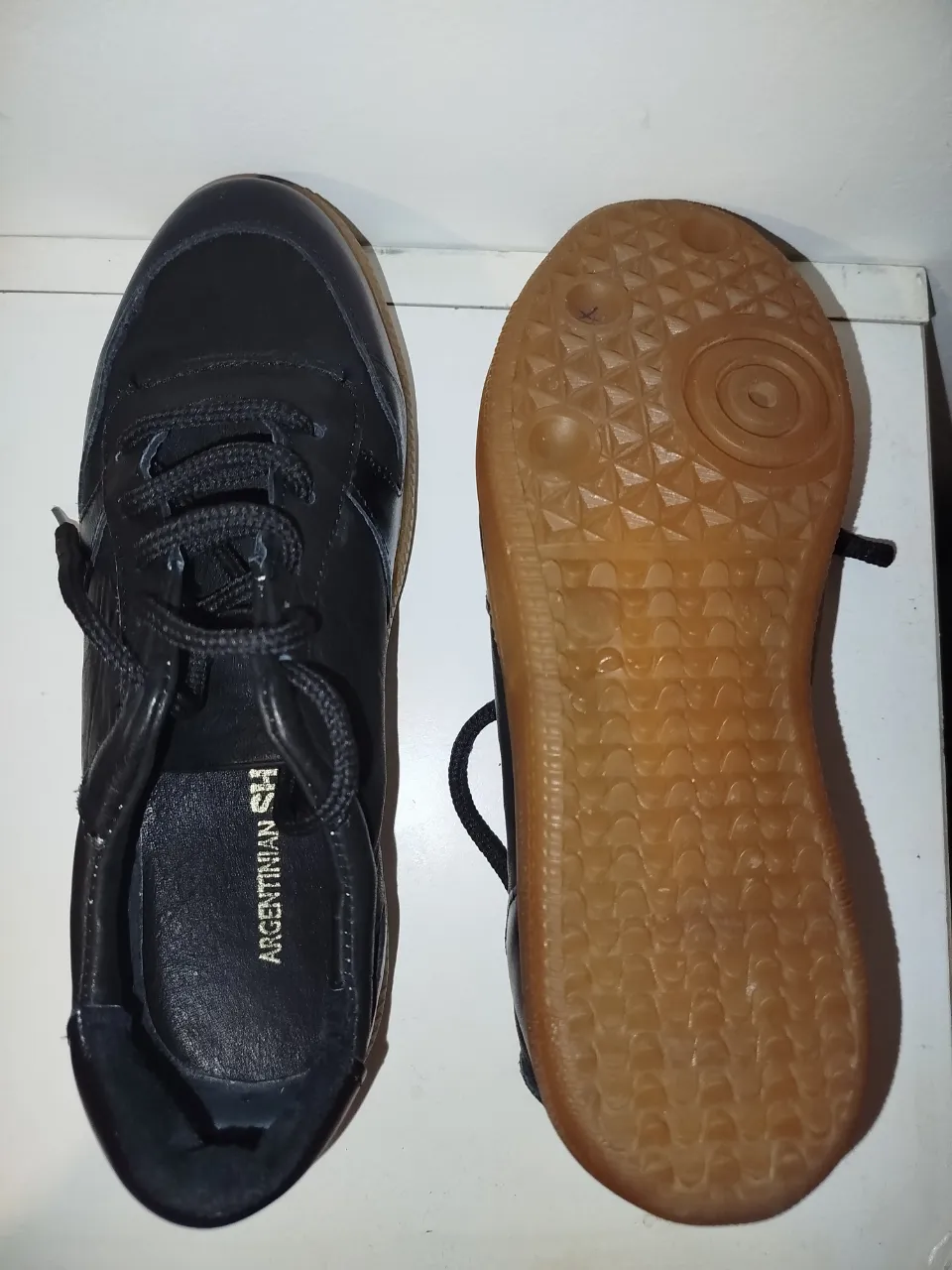 Zapatillas de cuero negro con suela marrón. Estilo clásico y versátil, ideales para uso diario. Marca Argentinian SH.