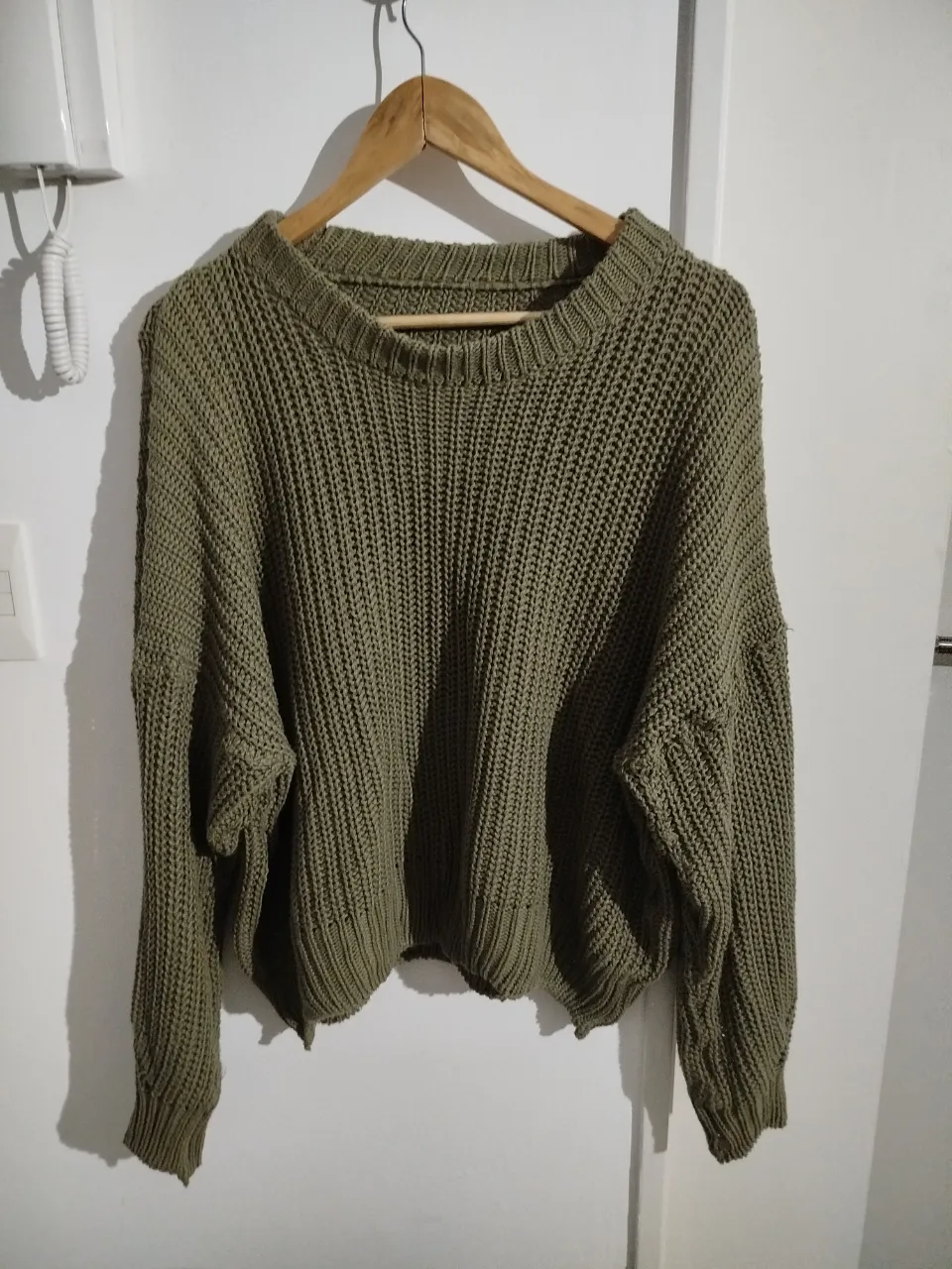 Sweater de punto grueso en color verde oliva, ideal para un look casual y abrigado. Cuello redondo y mangas amplias, perfecto para combinar con jeans o pantalones de vestir.