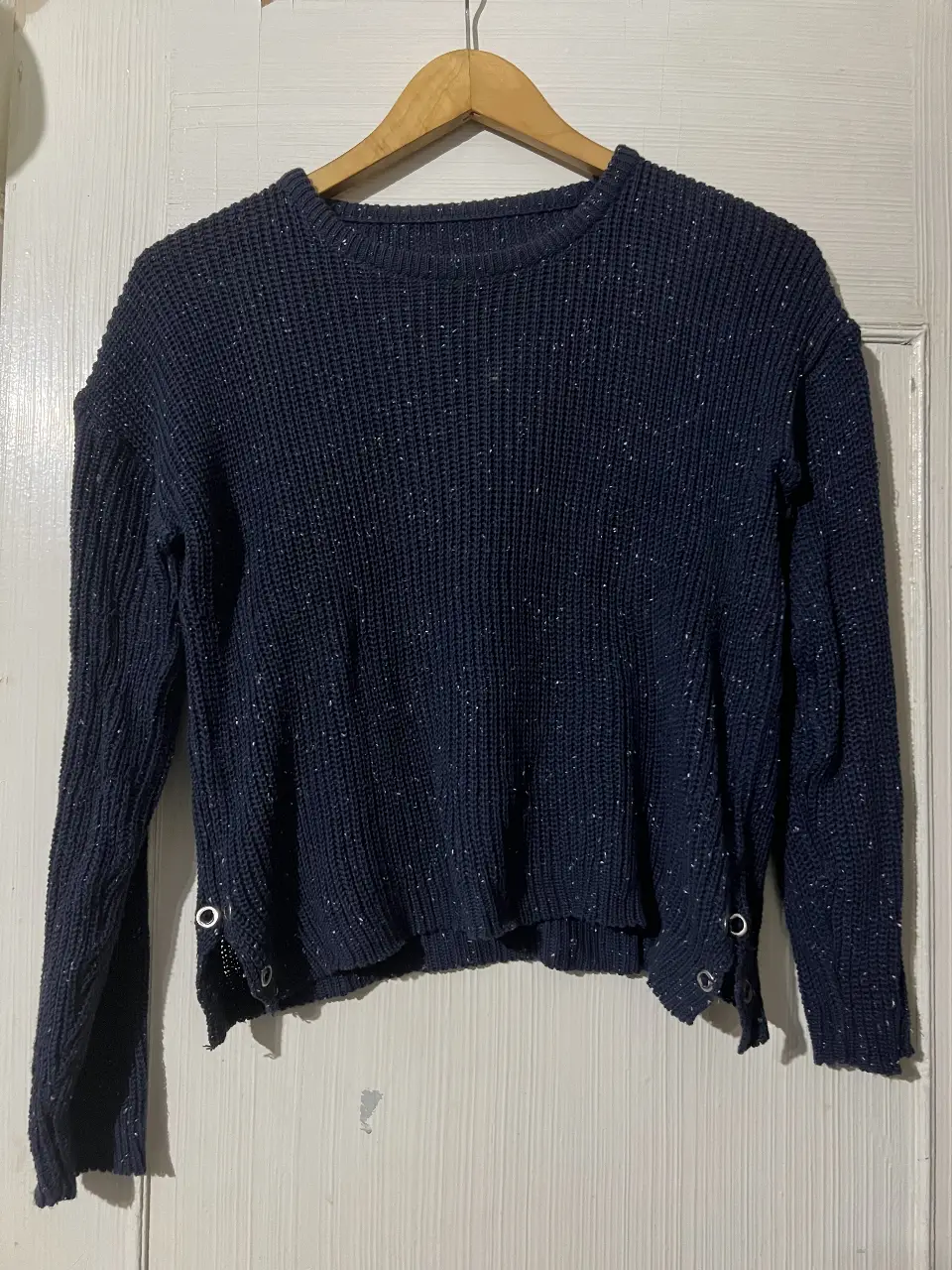 Sweater de punto azul marino con detalles de ojales en los laterales. Ideal para un look casual y abrigado.