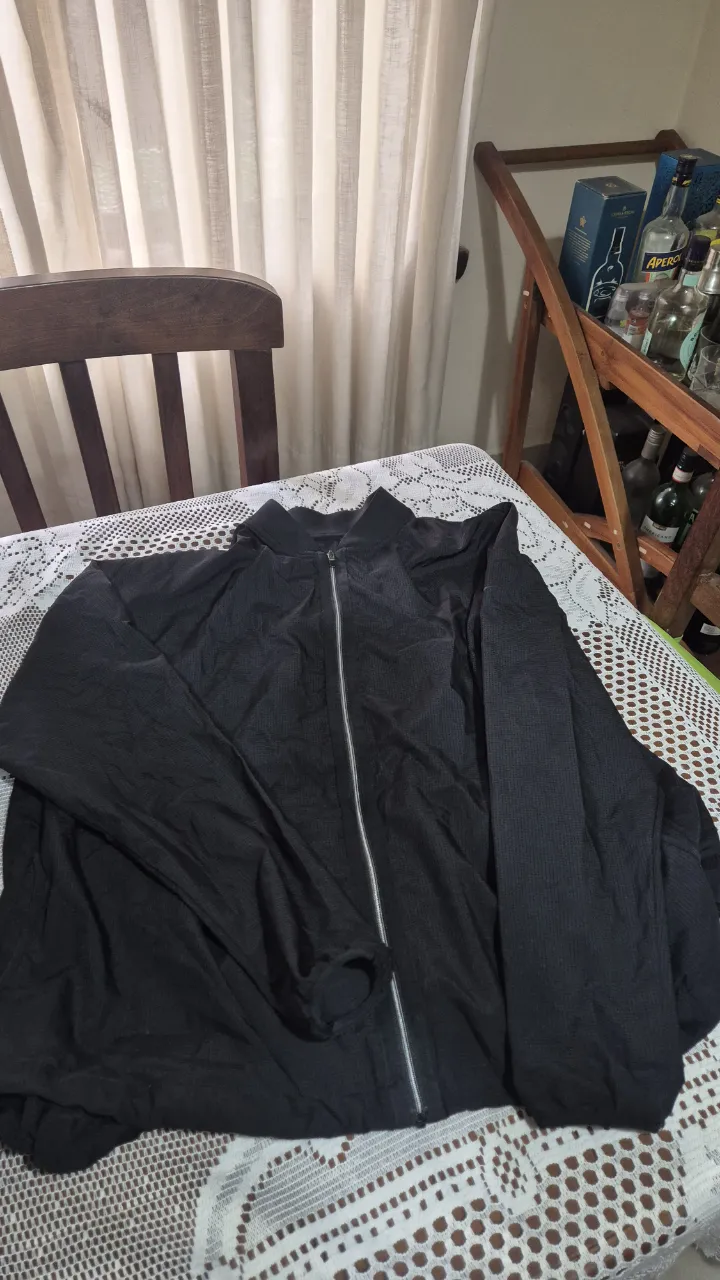 Campera negra con cierre central plateado y cuello alto.