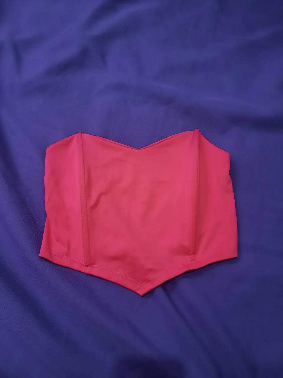 Top color fucsia con escote en V y detalles en la parte inferior.