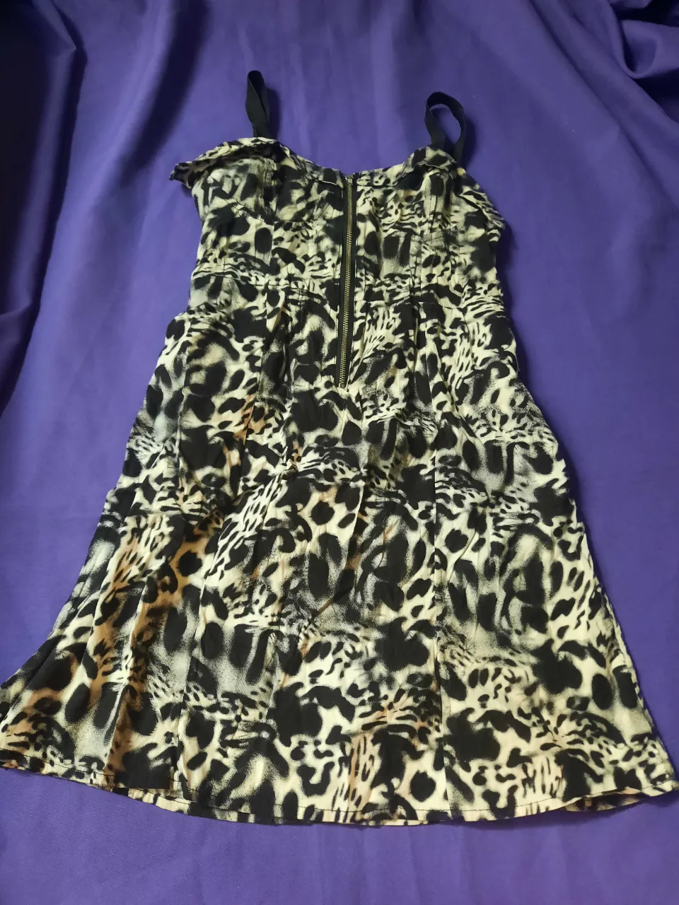 Vestido corto con estampado animal print en blanco y negro. Posee cierre metálico al frente y tiras finas. 