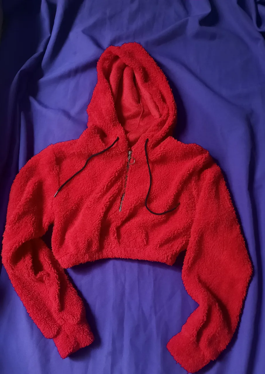 Buzo crop rojo con capucha y cierre metálico al frente. Cordones negros para ajustar la capucha.