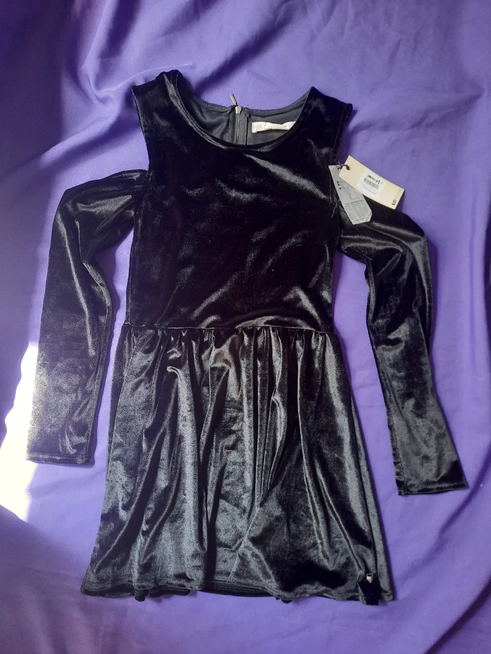 Vestido negro de terciopelo con mangas largas y hombros descubiertos. Cierre en la espalda.