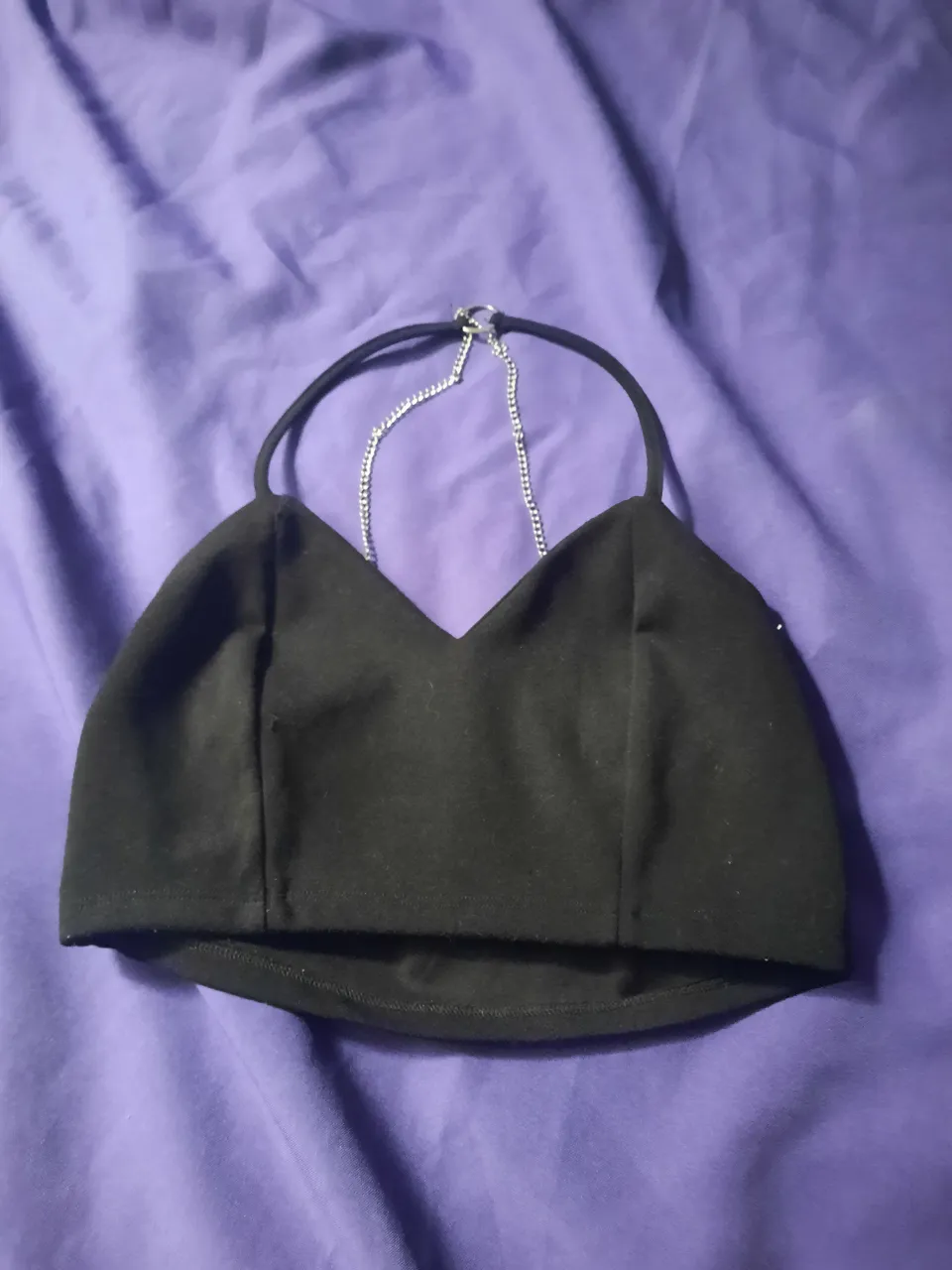 Top negro con tiras finas y detalle de cadena metálica en la espalda.