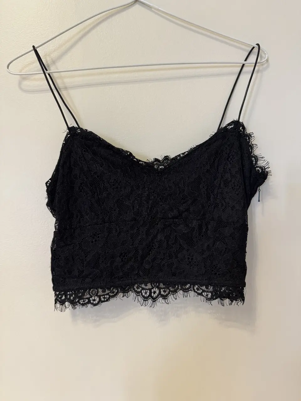 Top de encaje negro con tirantes finos y detalle de encaje en el borde. Tiene cierre en un lateral. Ideal para una salida.