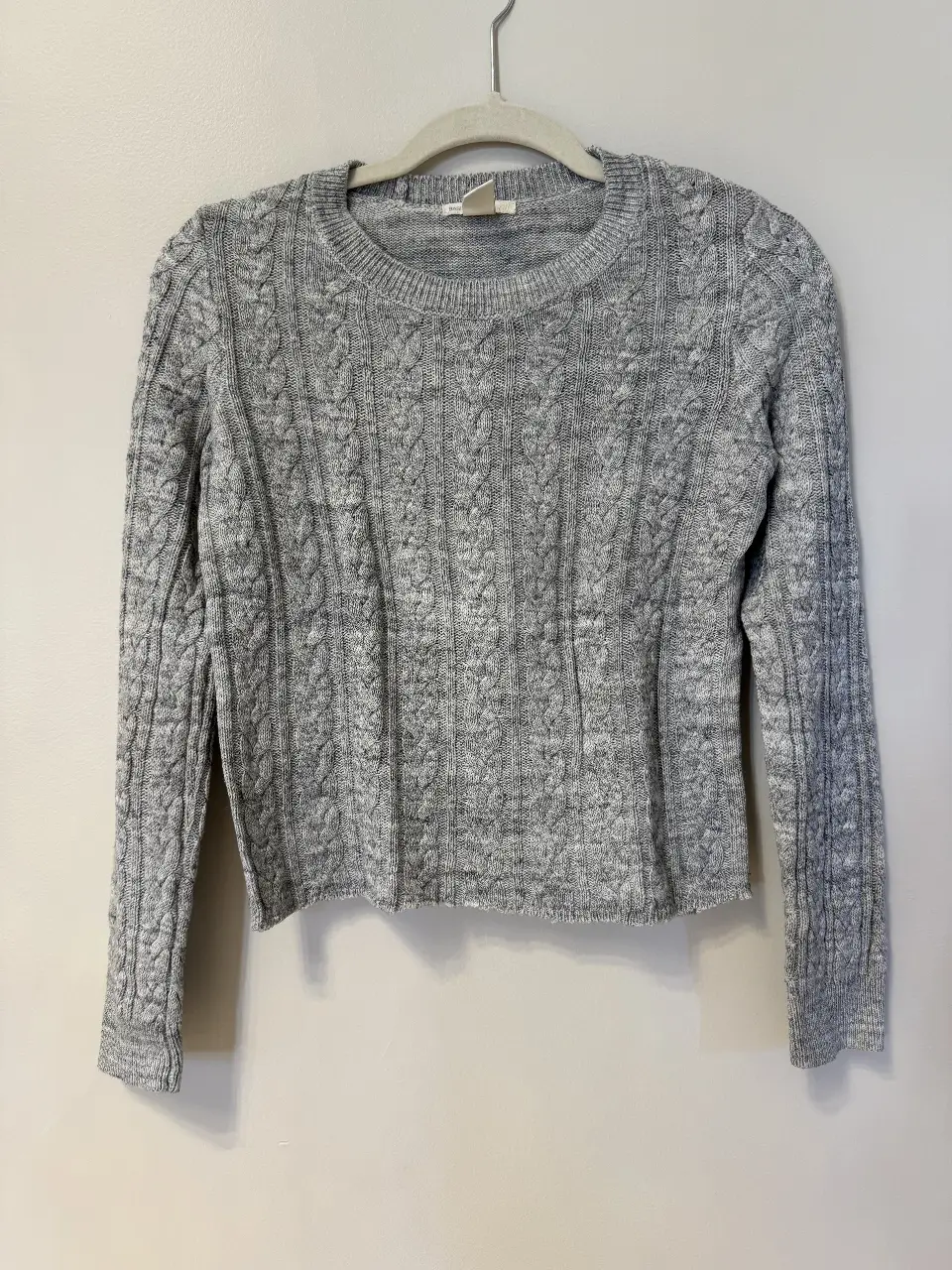 Sweater gris de punto con diseño de trenzas. Ideal para un look casual y abrigado.