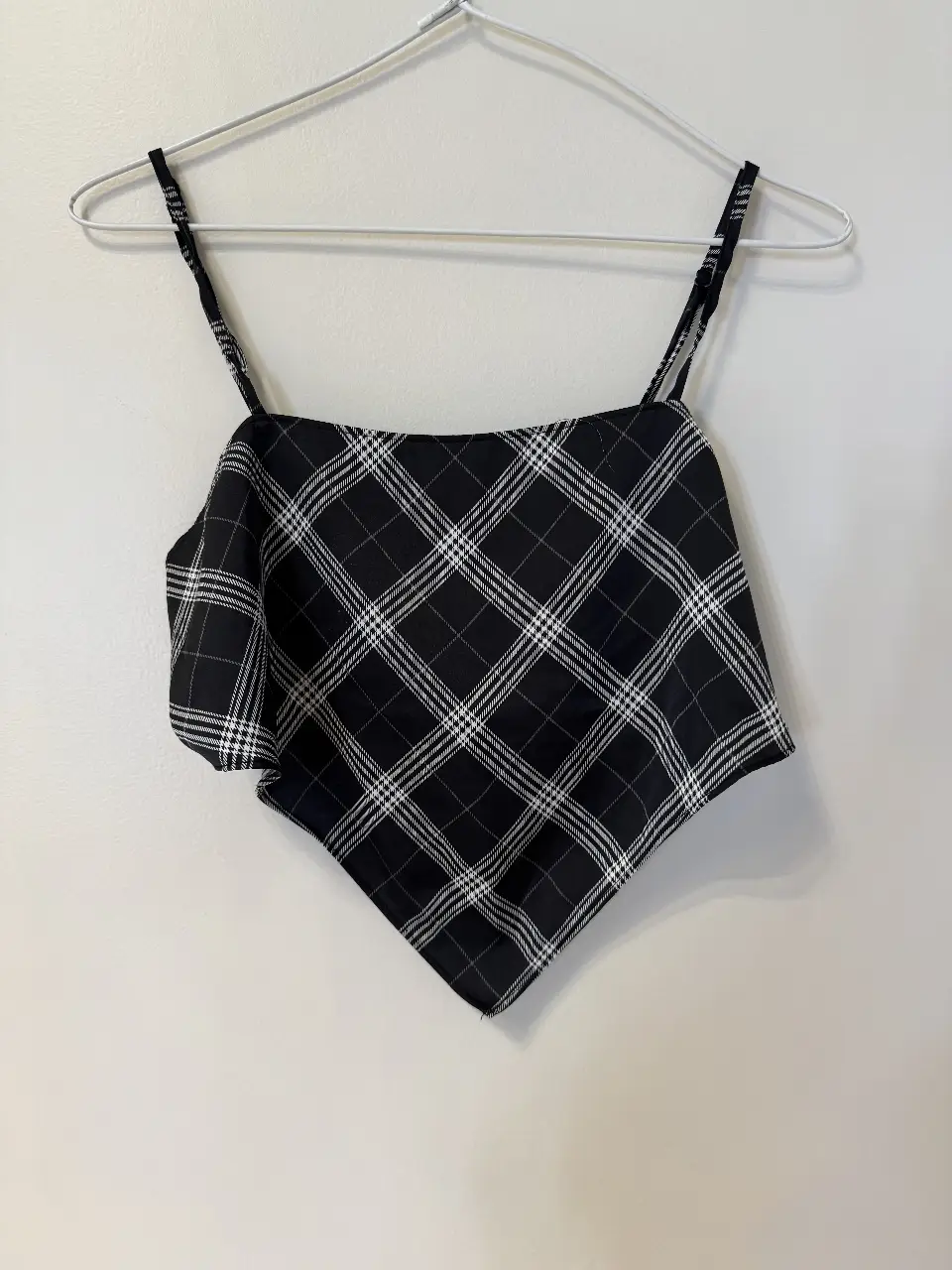 Top de mujer con estampado a cuadros en blanco y negro. Diseño con tirantes finos y detalle de volado en la parte delantera. Ideal para un look casual y moderno.