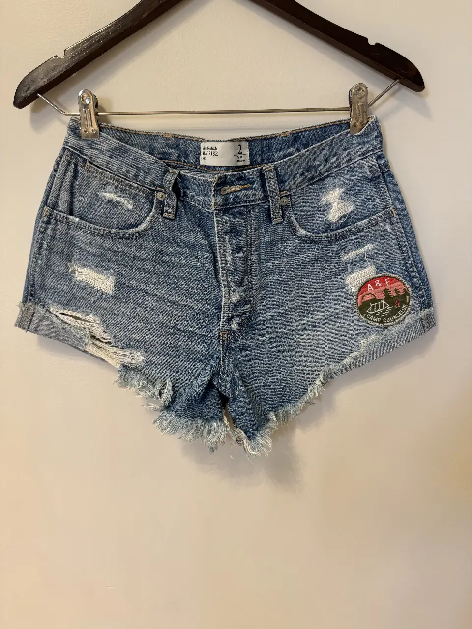 Short de jean de mujer Abercrombie & Fitch, tiro medio, con detalles rotos y parche en la parte trasera. Talle 2, W26. Ideal para un look casual y moderno.