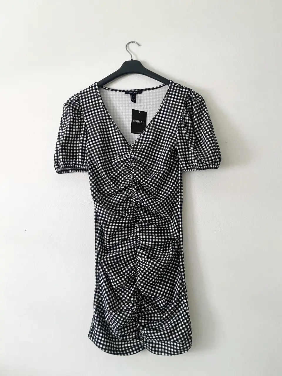Vestido  de Forever 21 con estampado de cuadros vichy en blanco y negro. Diseño fruncido en la parte delantera y mangas cortas abullonadas. Súper elastizado, se amolda a tu cuerpo