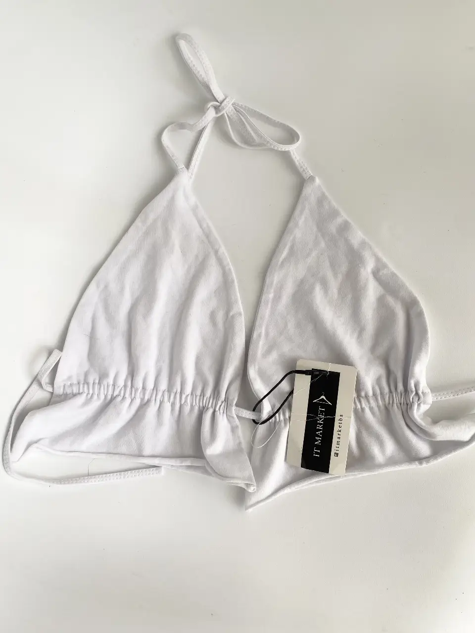 Top  blanco con fruncido y etiqueta de la marca IT MARKET. Los triangulos son regulables. Se ata en la espalda y cuello. Puse talle porque me pedía pero puede ir de un 80 a un 90/95.
