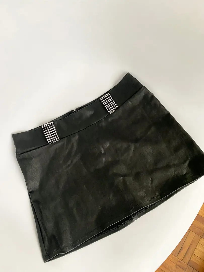 Minifalda negra de cuero sintético con detalles de strass en la cintura. Las tiras de strass se pueden cortar. Es elastizada, va tiro medio/tiro bajo. La foto es solo refe, me queda un poco grande. Puse cualquier talle, recomiendo ver medidas!