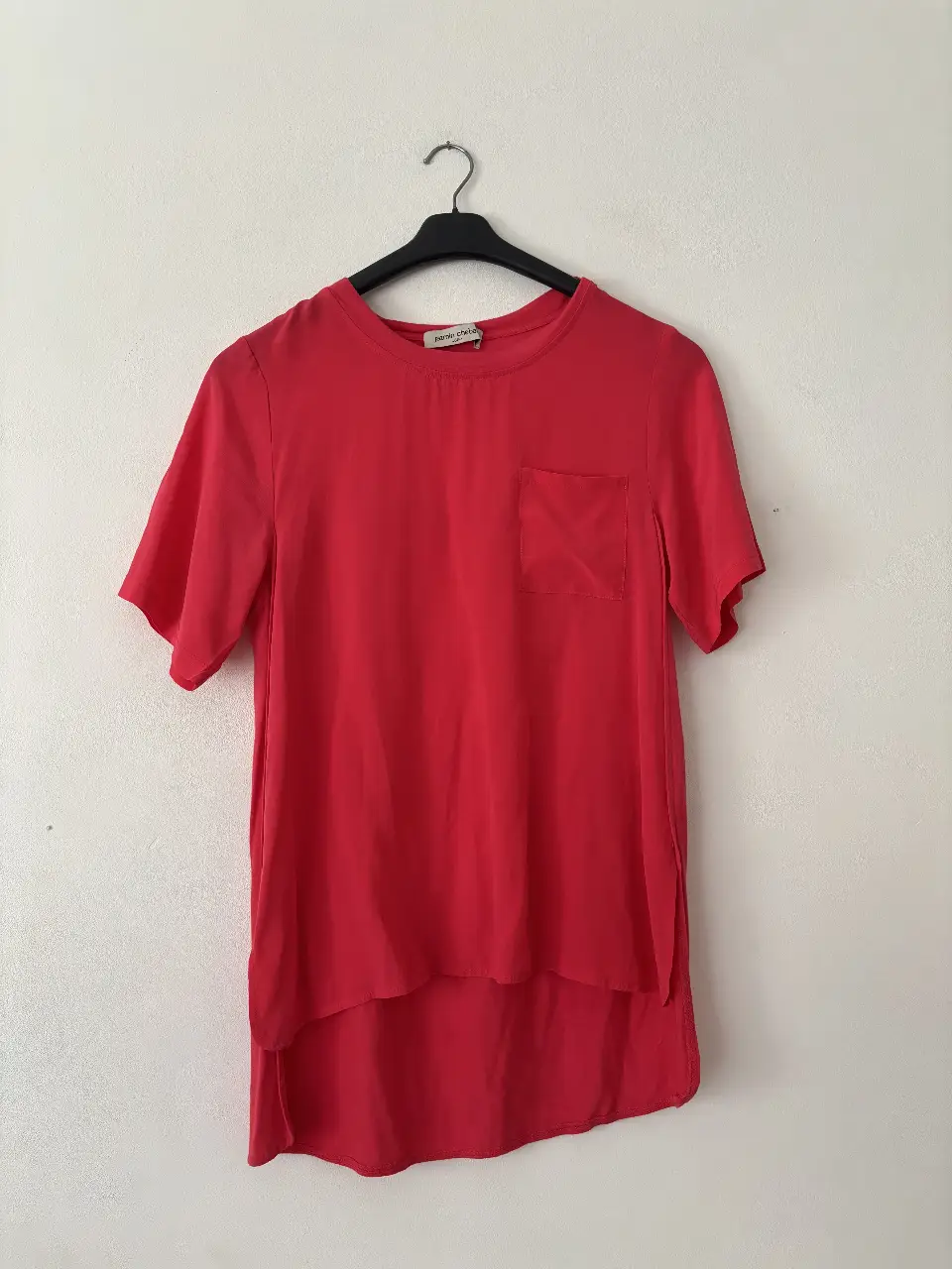 Remera roja/rosa de Jazmin Chebar, con bolsillo en el pecho y corte asimétrico. Para mi es un M. Hermosa calidad 55% seda. No bajan de 100k🤭