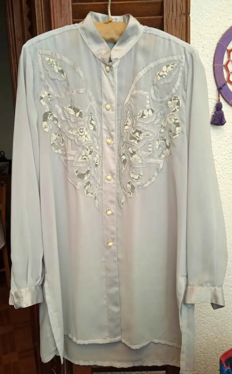 Blusa vintage de organza color celeste pastel, es un poco transparente con detalles de encaje y bordados florales en el frente. 
Mangas largas con puños satinados y botones nacarados. 
Tiene dos detalles, una manchita en la espalda alta cerca del hombro izquierdo (ver foto) y un botón casi caído, se puede coser.