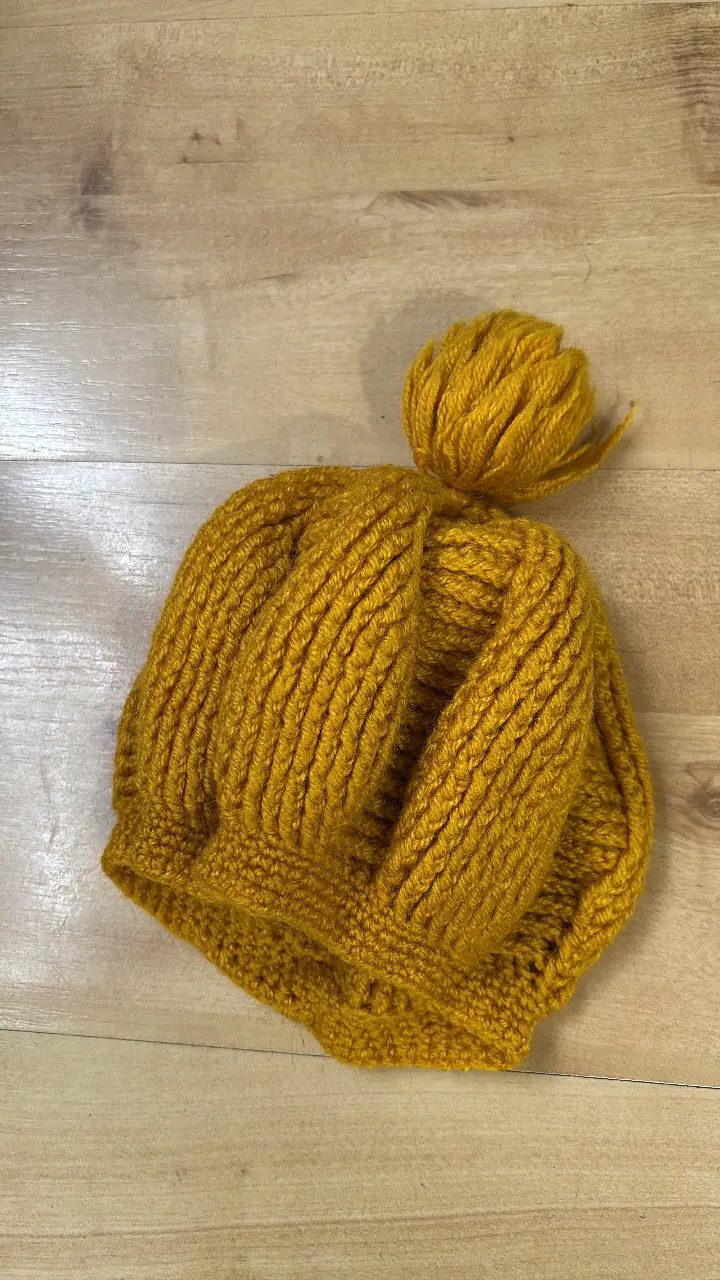 Gorro tejido a crochet en color mostaza, con detalle de pompón en la parte superior. Ideal para el invierno.